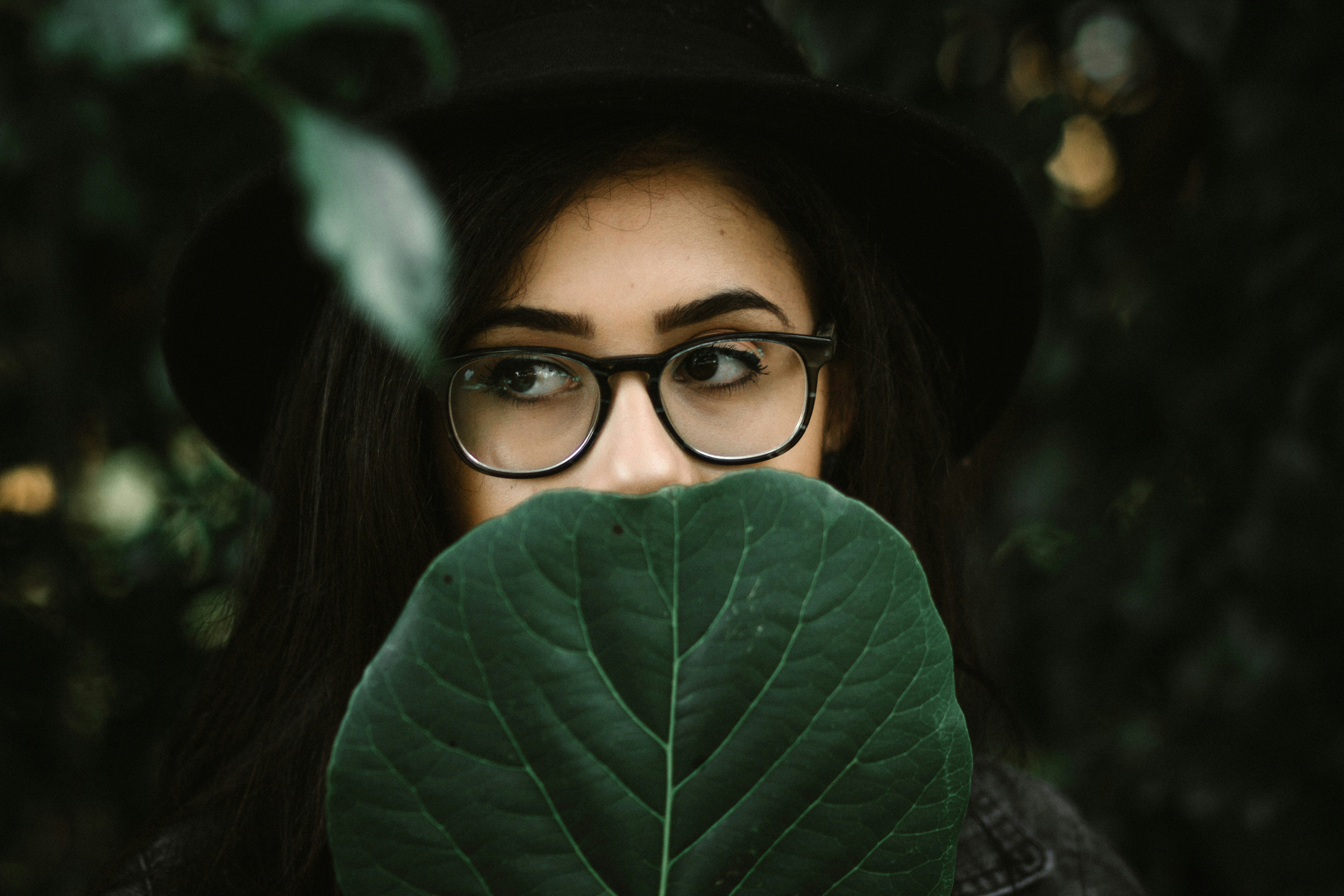 woman covering her mouth with green leaf